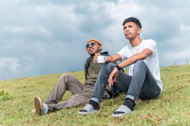 İki Endonezyalı adam kamp gezisinde bir fincan kahve içiyorlar.