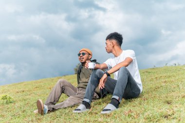 İki Endonezyalı adam kamp gezisinde bir fincan kahve içiyorlar.