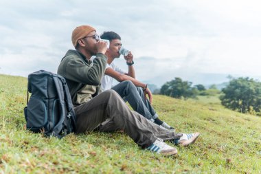 İki Endonezyalı adam kamp gezisinde bir fincan kahve içiyorlar.