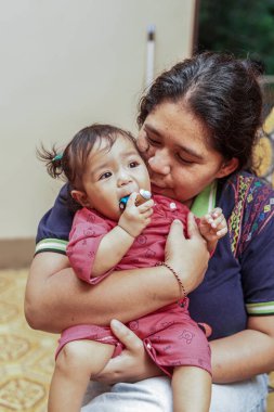Genç bir anne, parlak ve renkli bir kanepede sevgi, neşe ve gerçek aile bağını gösteren, küçük kızıyla evde oynar..