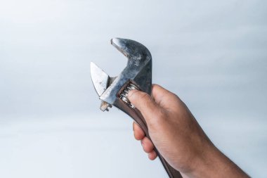 Beyaz arka planda ayarlanabilir anahtarı tutan Asyalı bir elin yakın çekimi. Tamir, inşaat, mekanik ve araçla ilgili içerik için mükemmel.