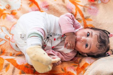 Renkli bir battaniyeye uzanmış, sıcak giysiler içinde tatlı bir Endonezyalı bebek. Çocukluk, ebeveynlik, aile hayatı, masumiyet ve Güneydoğu Asya kültürü konuları için mükemmel.