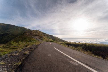 Gün doğumunda yemyeşil tepelerde kıvrımlı dağ yolu dönüyor. Seyahat, macera ya da metin kaplaması için alanı olan doğa temalı projeler için huzurlu, uzak ve mükemmel.