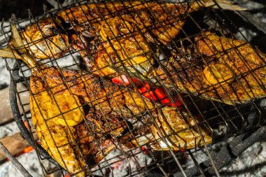 Terbiye edilmiş balık, üstünde limon dilimleri olan sıcak kömürün üstünde ızgara. Otantik barbekü deniz ürünleri hazırlama, aşçılık, geleneksel yemekler ve yaz barbekü temaları için mükemmel..