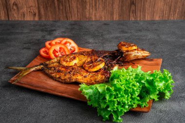 Izgara balık taze marul, domates dilimleri ve limonlu garnitürle servis edilir. Deniz ürünleri, sağlıklı beslenme, mutfak temaları, restoran menüsü tasarımı ve geleneksel mutfak için mükemmel..