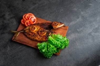 Izgara balık taze marul, domates dilimleri ve limonlu garnitürle servis edilir. Deniz ürünleri, sağlıklı beslenme, mutfak temaları, restoran menüsü tasarımı ve geleneksel mutfak için mükemmel..