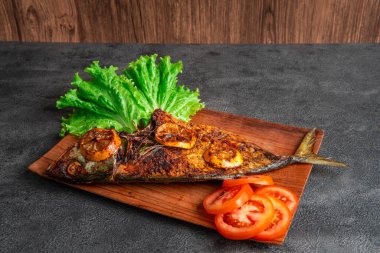 Izgara balık taze marul, domates dilimleri ve limonlu garnitürle servis edilir. Deniz ürünleri, sağlıklı beslenme, mutfak temaları, restoran menüsü tasarımı ve geleneksel mutfak için mükemmel..