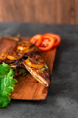 Izgara balık taze marul, domates dilimleri ve limonlu garnitürle servis edilir. Deniz ürünleri, sağlıklı beslenme, mutfak temaları, restoran menüsü tasarımı ve geleneksel mutfak için mükemmel..