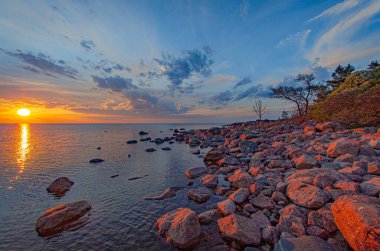 Kayalık bir sahilde renkli bir gün doğumu.