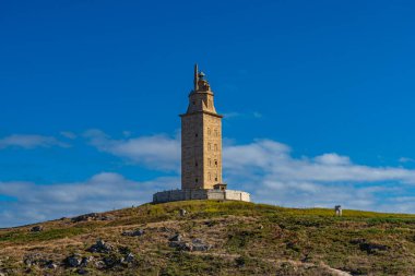 Herkül Kulesi açık mavi gökyüzü ile güneşli bir günde manzaraya bakıyor. Herkül Kulesi dünyanın en eski Roma deniz feneridir ve hala çalışır durumdadır..