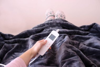 Elektrikli battaniye. Kadın elektrikli battaniyede ısıyı ayarlıyor.