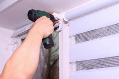 Pencereye tekerlekli jaluzi takan tornavidayla erkek ellerini kapat