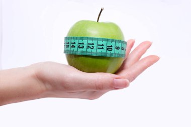 Yeşil elmayı elinde ölçü bandıyla tutan kadın. Sağlıklı beslenme ve kilo verme kavramı.
