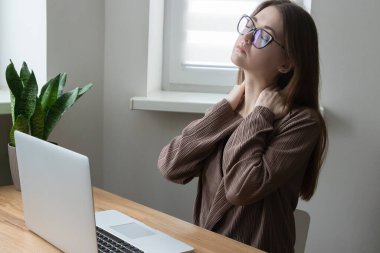 Çok çalışan genç bir kadın, ofis çalışanı, omuz omuza masaj yapan serbest çalışan biri. Bilgisayarda çalışırken boynu, omzu ağrıyormuş. Sabit yaşam biçimi.