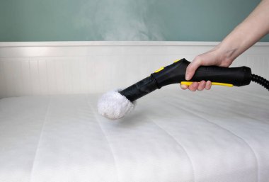 Toz akarları, bakteriler ve alerjenleri temizlemek için evdeki buhar temizleme yöntemini kullanarak yatağı sterilize etmek ve temizlemek..