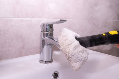 Ev temizliği. Buhar temizleme lavabosu musluğu ve buhar temizleyiciye bağlı mikrofiber bez. Zehirsiz, çevre dostu banyo temizliği..