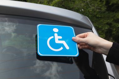 Engelli işareti takmak, arabanın arka camına engelli işareti koymak. Tekerlekli sandalye etiketi. 