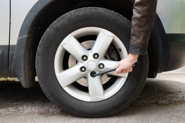 Adam tekerlek civatalarını sıkmak için el aleti kullanıyor. Otomotiv bakımı, araba tamiri ve yol güvenliği kavramı.