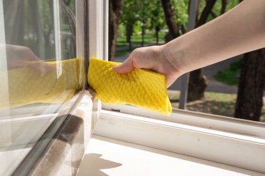 Pencere çerçevesindeki el temizleme tozu ve sarı bez ile. Ev temizliği kavramı