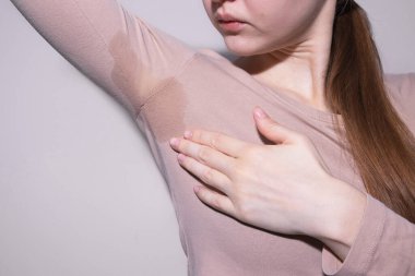 Koltuk altı ter izini kontrol eden genç bir kadın var. Hiperhidroz kavramı, aşırı terleme..