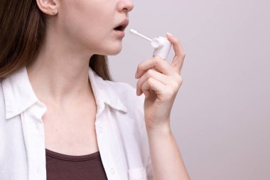 Hasta kadın boğaz ağrısını azaltmak için ilaçlı boğaz spreyi kullanıyor, acıyı yutuyor. Grip semptomları, larenjit ve soğuk algınlığı tedavisi.