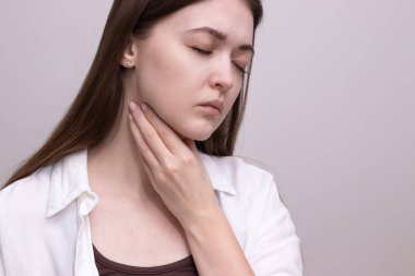 Boğazı ağrıyan, yutkunan, boynuna dokunan genç bir kadının yakın çekimi. Bademcik iltihabı, gırtlak iltihabı, mevsimsel hastalık belirtileri..