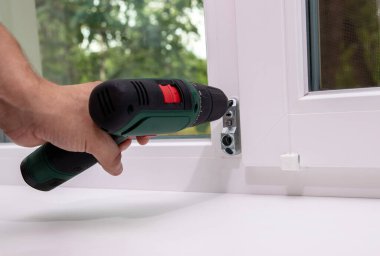 Plastik pencereye tornavidayla çocuk kilidi takan adam. Bebek güvenliği kavramı, ev güvenliği.