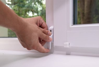 Çocuk güvenliği için pencere kilidi takan bir adam. Bebek güvenliği kavramı, ev güvenliği.