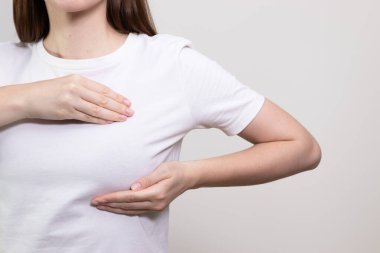 Kadın göğüs muayenesi yapıyor, şişlik ya da değişiklik var mı diye kontrol ediyor. Kanser önleme kavramı, göğüs kanseri farkındalığı, göğüs kontrolü.