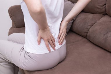 Kanepede oturan bir kadının dokunuşuna, sırtına masaj yapmasına. Sırt ağrısı, kronik sırt ağrısı, yerleşik yaşam tarzı, omurga gerilimi..