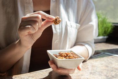 Kabuklu cevizli ceviz kabuğundan ceviz alan kadına yaklaş. Beyin yemeği, omega-3 beslenme ve sağlıklı atıştırmalık kavramı..