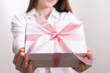 Elinde pembe kurdeleli beyaz hediye kutusu olan bir kadın. Kutlama anlayışı, bayram tebrikleri, hediye verme..