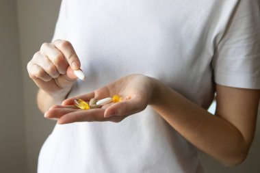 Çeşitli haplar ve takviyelerle bir kadının ellerini kaybetmek. Omega 3, omega 6, omega 9, balık yağı kapsülleri, D vitamini ve vitamin alan bir kadın. Kadınlar için vitaminler.