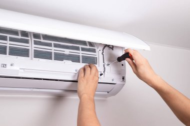 Teknisyen havalandırma ünitesini tamir etmek için tornavida kullanıyor. Elektrik tamiri, klima servisi, havalandırma bakımı....