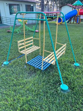 Old toy swing in grassy park on a sunny summer day 