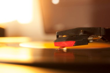 Vinil kayıt ve üreme iğnesinin detayları. Altın ışığın parıltısı diskin bir kısmına yansıyor. Müzik konsepti. Vinil konsepti