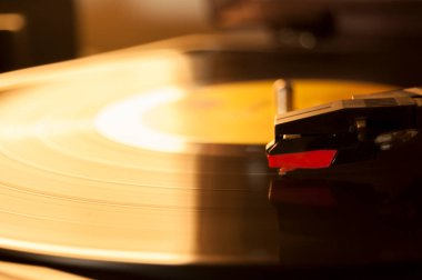 Vinil kayıt ve üreme iğnesinin detayları. Altın ışığın parıltısı diskin bir kısmına yansıyor. Müzik konsepti. Vinil konsepti