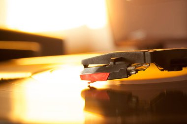 Vinil kayıt ve üreme iğnesinin detayları. Altın ışığın parıltısı diskin bir kısmına yansıyor. Müzik konsepti. Vinil konsepti