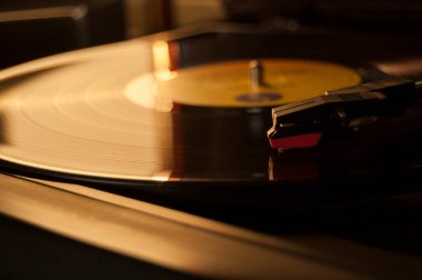 Vinil kayıt ve üreme iğnesinin detayları. Altın ışığın parıltısı diskin bir kısmına yansıyor. Müzik konsepti. Vinil konsepti