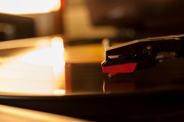 Vinil kayıt ve üreme iğnesinin detayları. Altın ışığın parıltısı diskin bir kısmına yansıyor. Müzik konsepti. Vinil konsepti