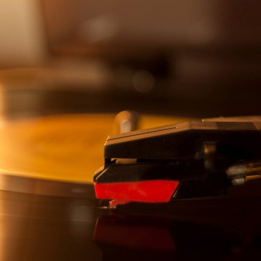 Vinil kayıt ve üreme iğnesinin detayları. Altın ışığın parıltısı diskin bir kısmına yansıyor. Müzik konsepti. Vinil konsepti