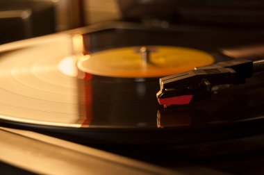 Vinil kayıt ve üreme iğnesinin detayları. Altın ışığın parıltısı diskin bir kısmına yansıyor. Müzik konsepti. Vinil konsepti