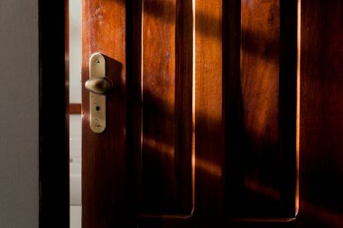 Otel odasının kapısı kilitli ve güneş ışığı yan taraftan içeri giriyor. Doğal ışık ve doğal ahşap. Kapı konsepti. Kilit kavramı.