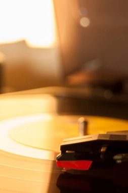 Vinil kayıt ve üreme iğnesinin detayları. Altın ışığın parıltısı diskin bir kısmına yansıyor. Müzik konsepti. Vinil konsepti