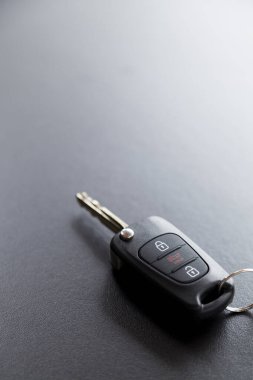 Arabanın anahtarı siyah bir masanın üstünde, üzerinde doğal ışık var. Kapıyı kilitleyip açmak için düğmeli anahtar. Araba anahtarı konsepti. Kapı kilidi kavramı. Boşluğu kopyala.