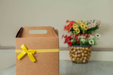 Arkasında sarı bir fiyonk ve çiçekler olan hediye paketi. Hediye konsepti. Sarı yay konsepti.