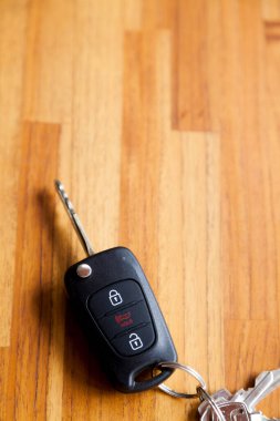 Arabanın anahtarı ahşap bir masanın üstünde. Kapıyı kilitleyip açmak için düğmeli anahtar. Araba anahtarı konsepti. Elektrik kilidi kavramı.