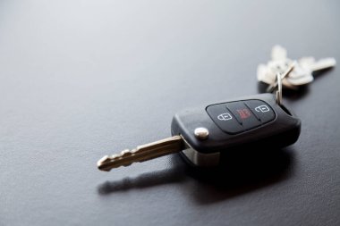 Arabanın anahtarı siyah bir masanın üstünde, üzerinde doğal ışık var. Kapıyı kilitleyip açmak için düğmeli anahtar. Araba anahtarı konsepti. Kapı kilidi kavramı. Boşluğu kopyala.