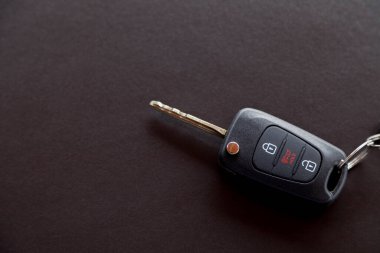 Arabanın anahtarı siyah bir masanın üstünde, üzerinde doğal ışık var. Kapıyı kilitleyip açmak için düğmeli anahtar. Araba anahtarı konsepti. Kapı kilidi kavramı. Boşluğu kopyala.