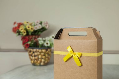 Arkasında sarı bir fiyonk ve çiçekler olan hediye paketi. Hediye konsepti. Sarı yay konsepti.